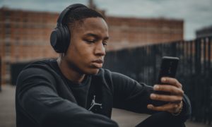 a man looking at his phone with headphones with bluetooth technology on